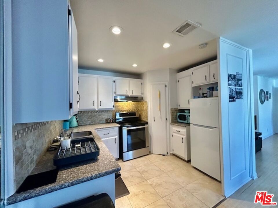a kitchen with a refrigerator a stove top oven a sink and cabinets
