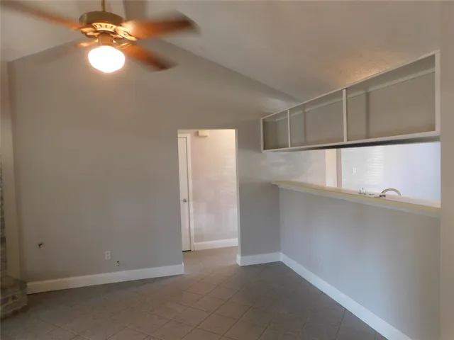 a view of an empty room with window and chandelier fan
