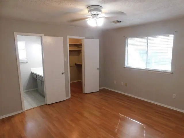a view of empty room with wooden floor and fan