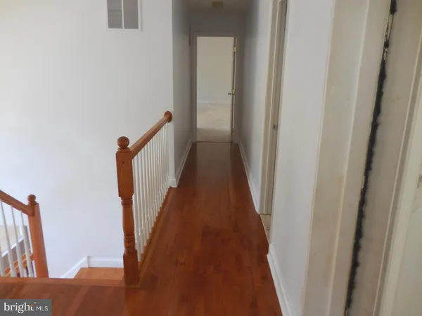 a view of a hallway with wooden floor and stairs