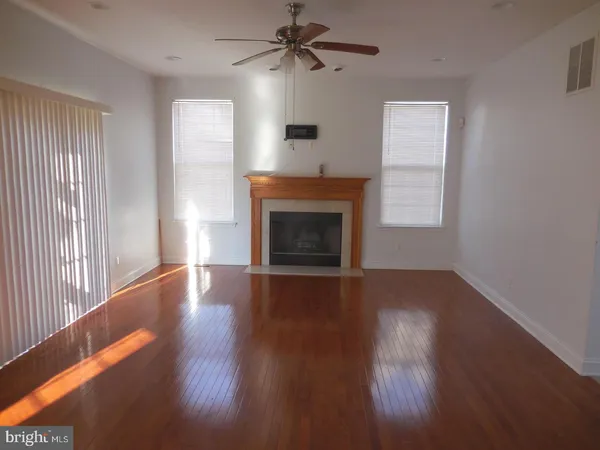 an empty room with wooden floor fireplace and windows