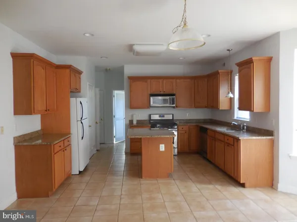 a large kitchen with stainless steel appliances wooden cabinets a stove a sink and a refrigerator