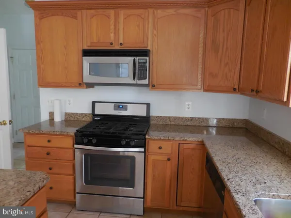 a kitchen with granite countertop a stove top oven microwave and cabinets