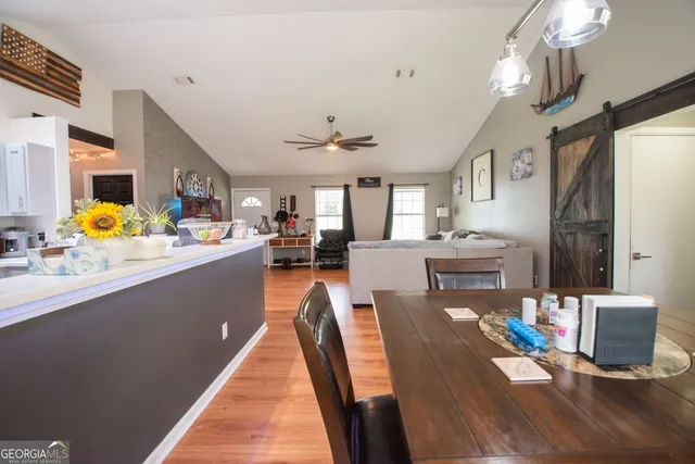 a living room with dining room furniture kitchen view and a large window