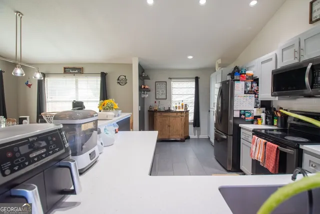 a kitchen with stainless steel appliances kitchen island granite countertop a refrigerator a stove a sink dishwasher a dining table and chairs with wooden floor