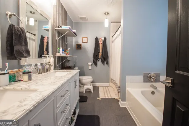 a bathroom with a granite countertop sink a toilet a mirror and shower