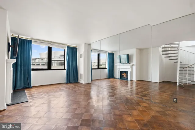 a view of an empty room with window and wooden floor