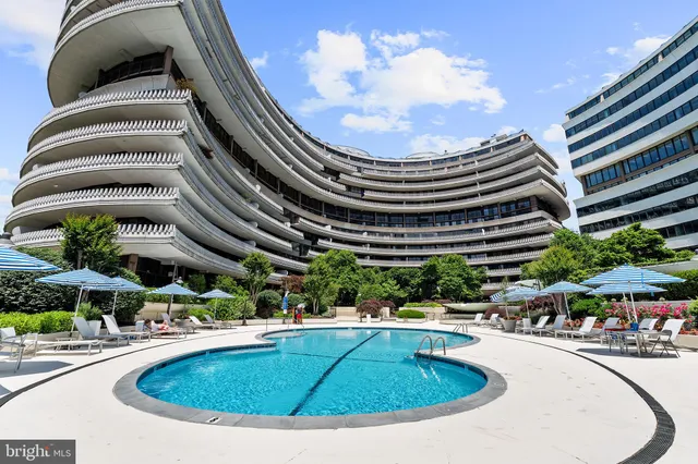 an aerial view of a house with swimming pool and large trees