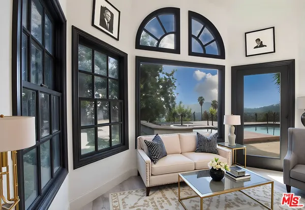 a living room with furniture a floor to ceiling window and a flat screen tv