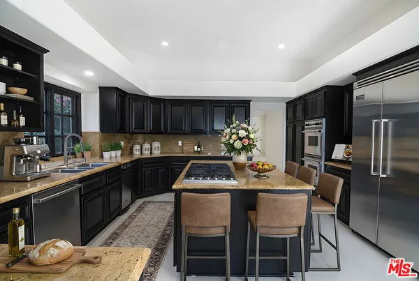 a kitchen with granite countertop kitchen island stainless steel appliances a sink stove and refrigerator