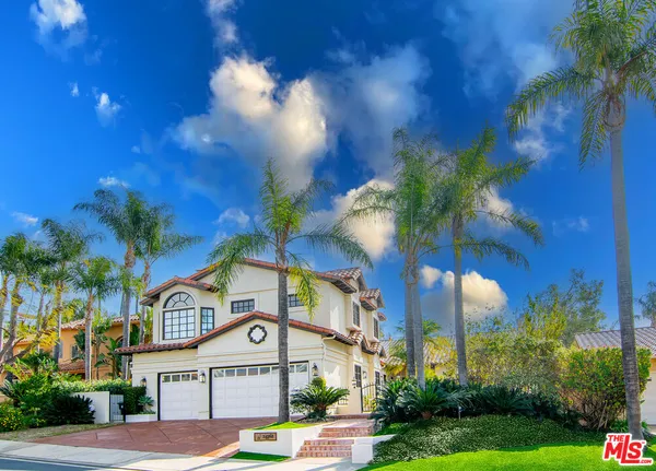 a front view of a house with a small yard and palm trees
