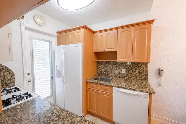 a kitchen with stainless steel appliances granite countertop a refrigerator and a stove