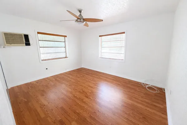 a view of a big room with wooden floor and windows