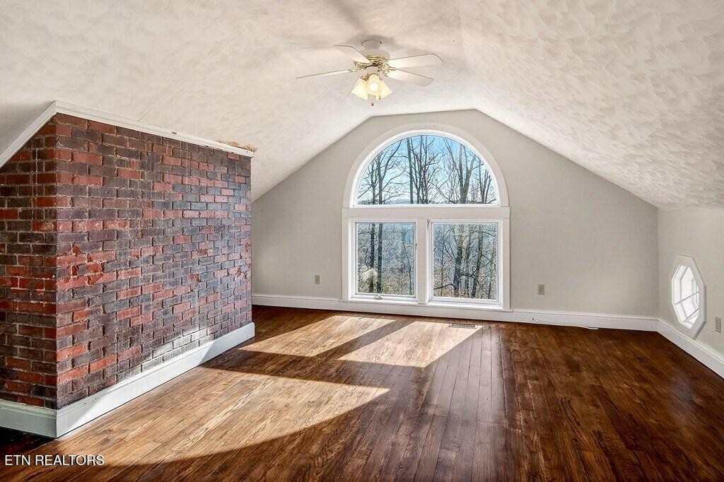 6211 Rocky Point Road Cookeville, TN 38506 - Photo 53 of 59 an empty room with wooden floor chandelier fan and windows