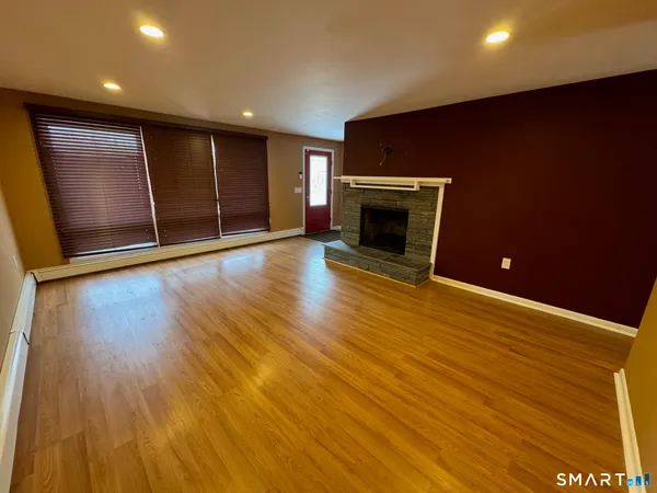 a view of an empty room with wooden floor and a fireplace