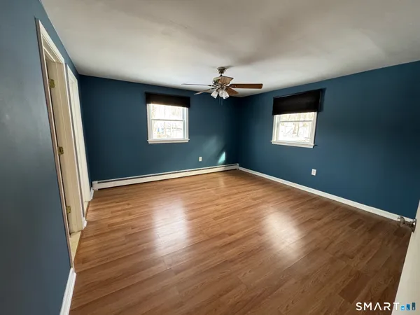 an empty room with wooden floor and windows