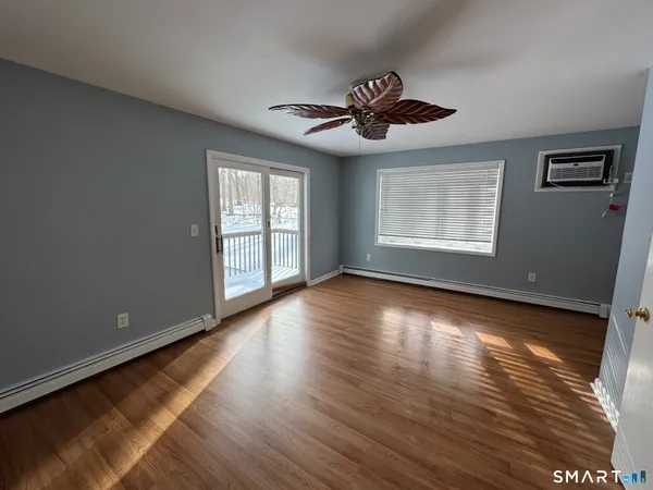 a view of an empty room with wooden floor and a window