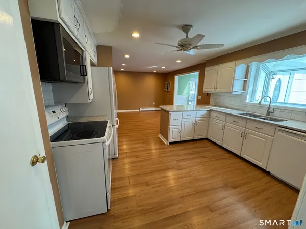 a large kitchen with stainless steel appliances granite countertop a sink a stove and a refrigerator