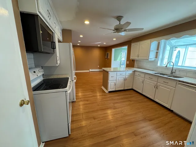 a large kitchen with stainless steel appliances granite countertop a sink a stove and a refrigerator