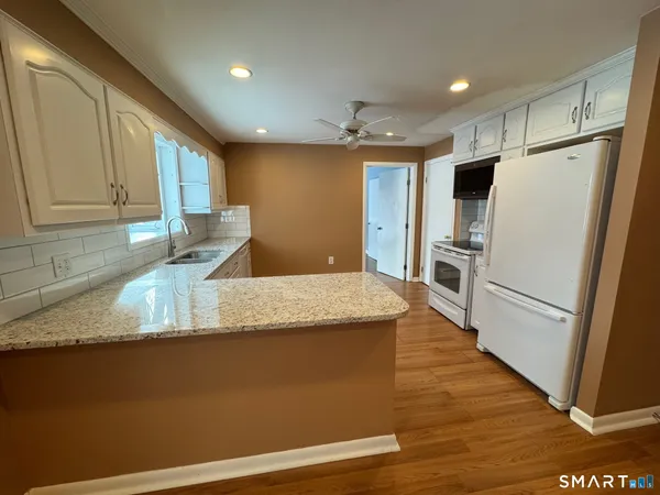a kitchen with granite countertop a refrigerator a sink and dishwasher