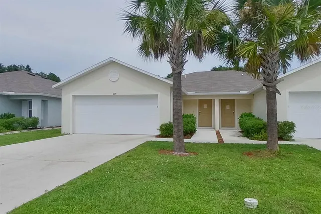 a front view of a house with a yard and palm trees