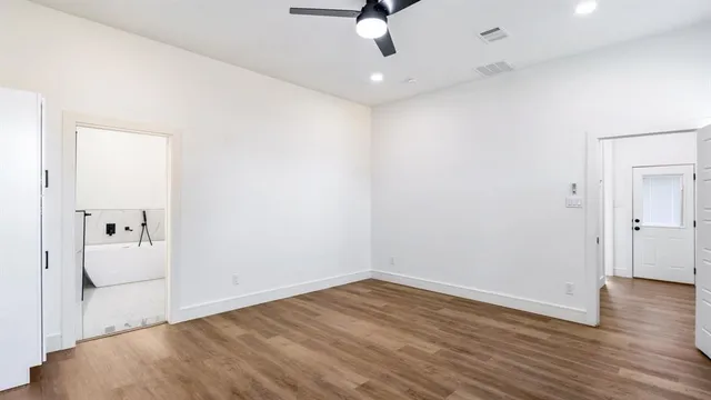 an empty room with wooden floor and ceiling fan