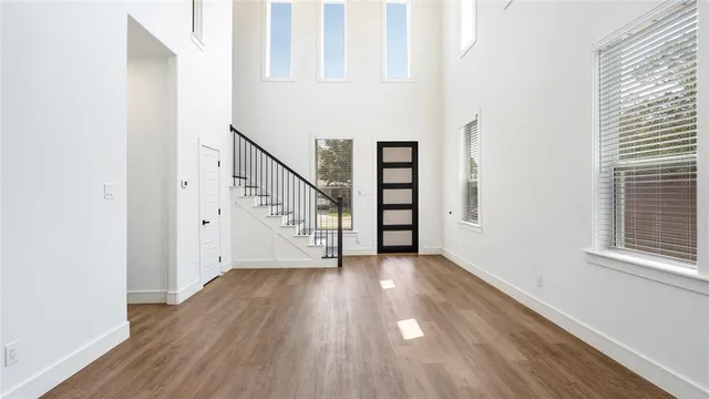 a view of an empty room with wooden floor and stairs