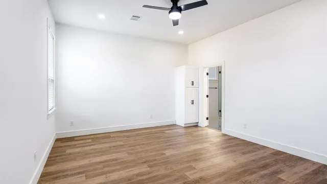 an empty room with wooden floor and ceiling fan