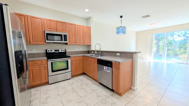 a kitchen with stainless steel appliances granite countertop a stove top oven a sink a refrigerator and white cabinets
