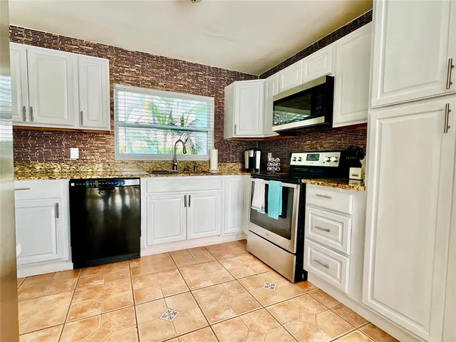 a kitchen with stainless steel appliances granite countertop a stove a sink and a refrigerator