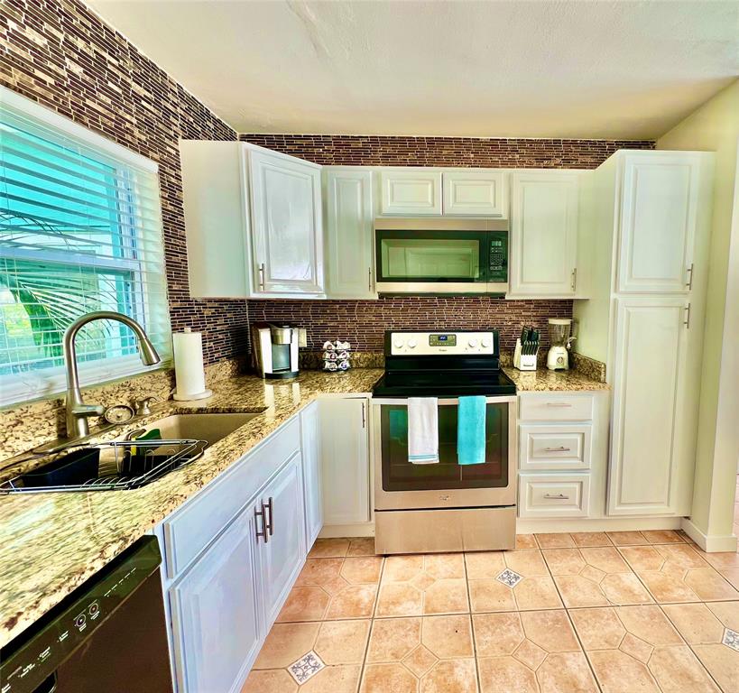 133 Northeast 1st Street Satellite Beach, FL 32937 - Photo 10 of 27 a kitchen with stainless steel appliances granite countertop a sink stove and cabinets
