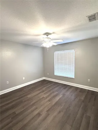 a view of an empty room with window and wooden floor