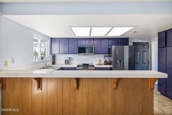 a kitchen with stainless steel appliances granite countertop a sink a refrigerator and a granite counter tops with wooden floors