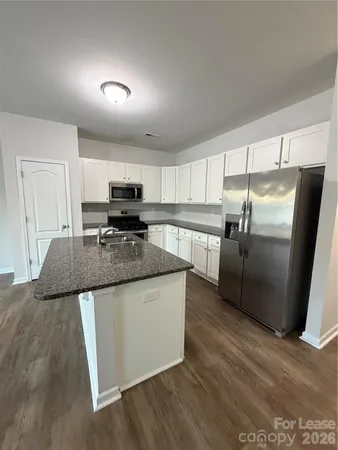 a kitchen with stainless steel appliances granite countertop a refrigerator a stove a sink and a microwave