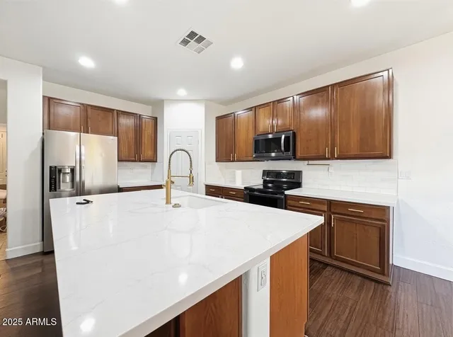 a kitchen with granite countertop wooden cabinets stainless steel appliances and a sink