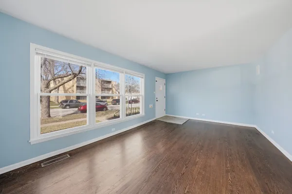 an empty room with wooden floor and large window