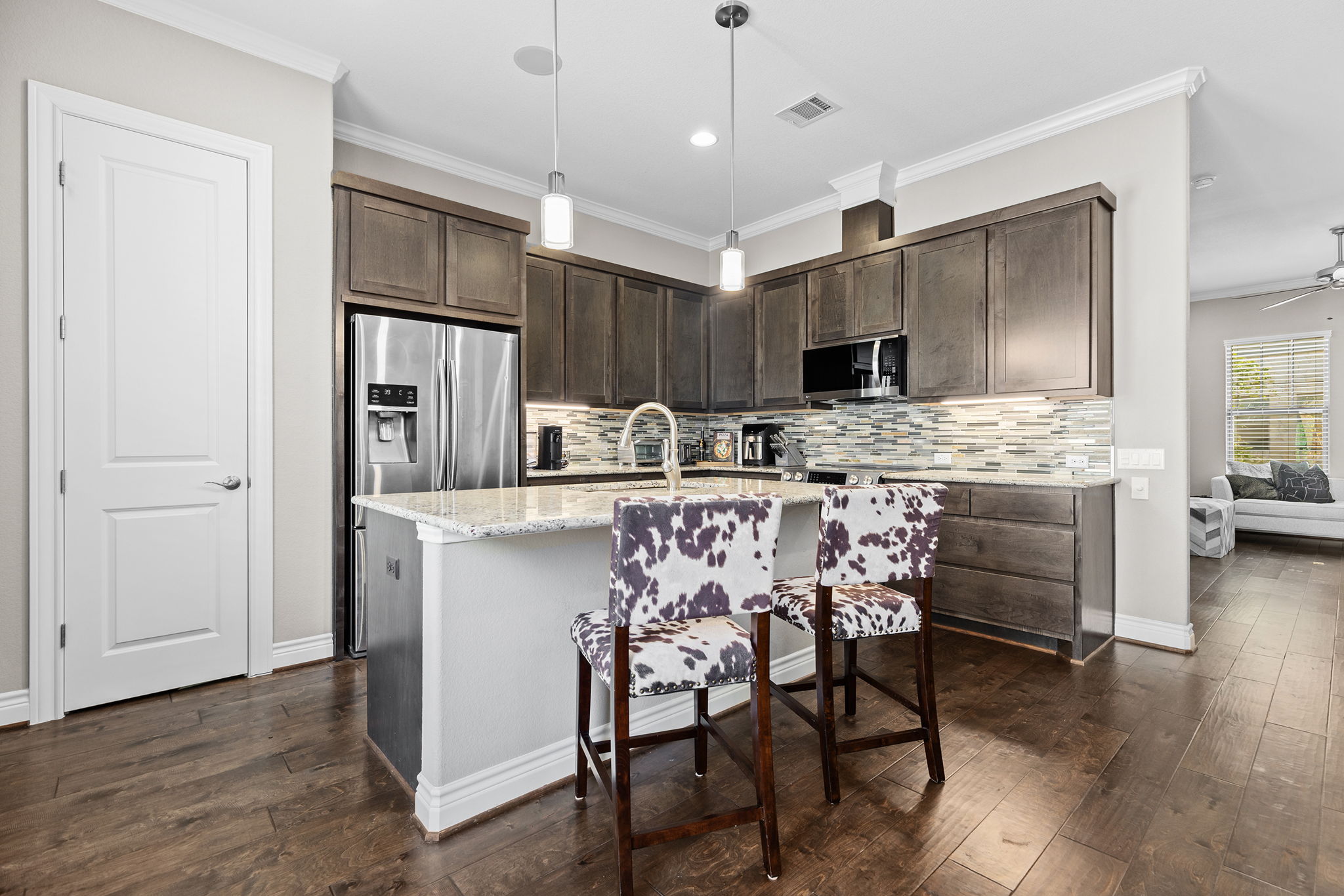 1125 Highknoll Lane Georgetown, TX 78628 - Photo 11 of 40 Kitchen featuring dark wood finish cabinetry, light stone counters, dark wood finished floors, an island with sink, and ornamental molding