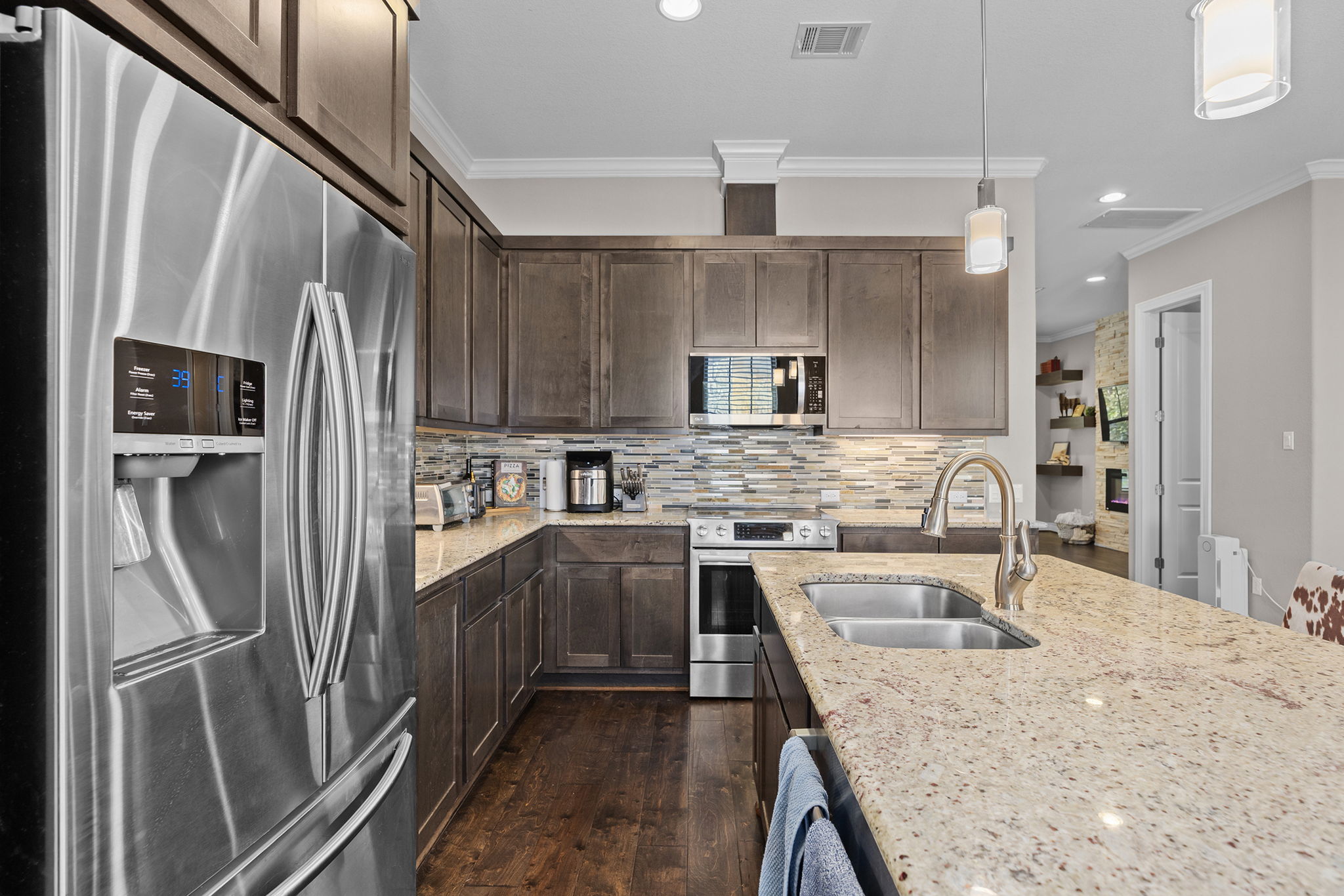1125 Highknoll Lane Georgetown, TX 78628 - Photo 2 of 40 Kitchen featuring stainless steel appliances, pendant lighting, light stone countertops, dark wood finished floors, and crown molding