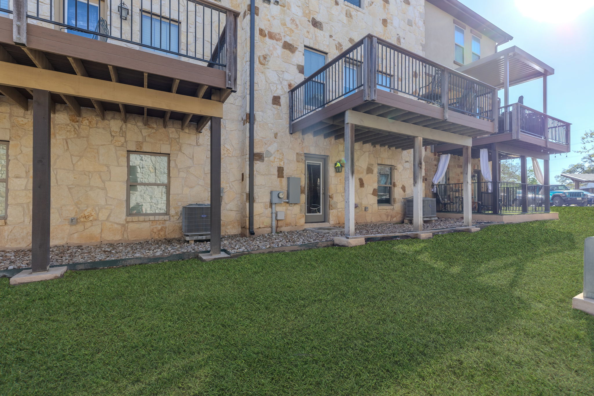 1125 Highknoll Lane Georgetown, TX 78628 - Photo 37 of 40 Rear view of house featuring stone siding, a yard, a deck, and a balcony