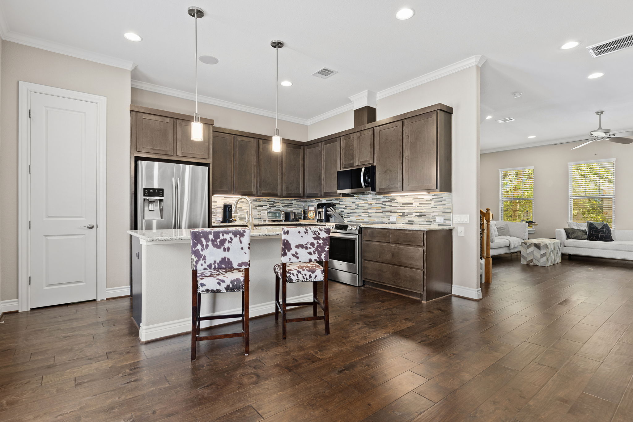 1125 Highknoll Lane Georgetown, TX 78628 - Photo 10 of 40 Kitchen with stainless steel appliances, an island with sink, decorative backsplash, ornamental molding, and dark wood-style floors