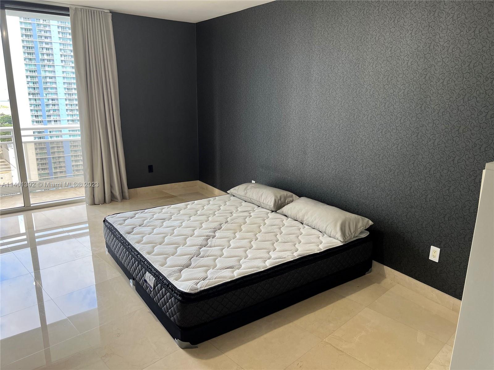 901 Brickell Key Boulevard, Unit 2506 Miami, FL 33131 - Photo 18 of 24 a bed sitting in a bedroom next to a window