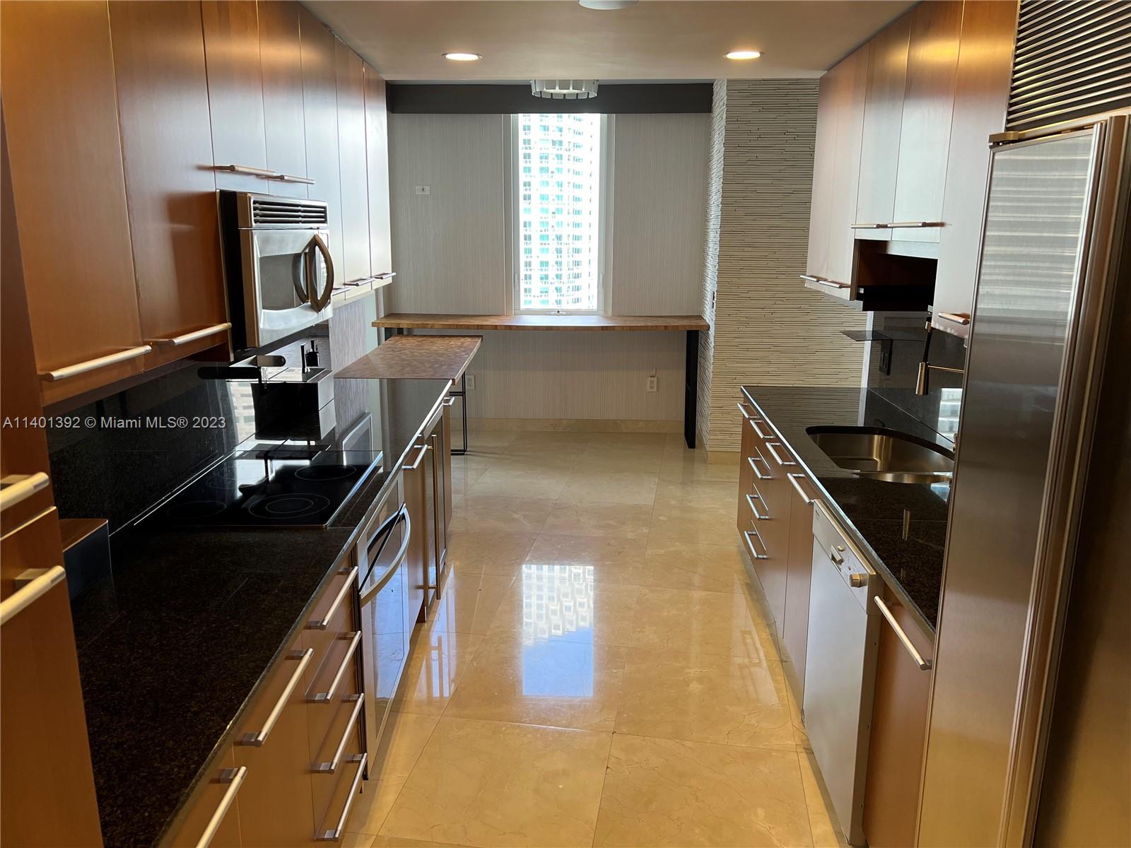 901 Brickell Key Boulevard, Unit 2506 Miami, FL 33131 - Photo 3 of 24 a kitchen with black countertop appliances a sink and a counter top space