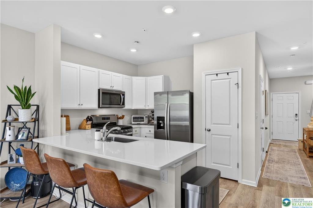 1274 Martin Road Breinigsville, PA 18031 - Photo 5 of 18 An open kitchen layout features clean white cabinetry, solid stone countertops, and classic wood-look flooring.