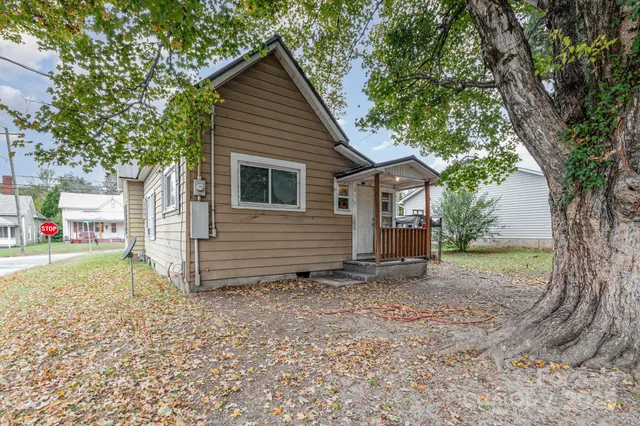 a view of a house with a yard and large tree