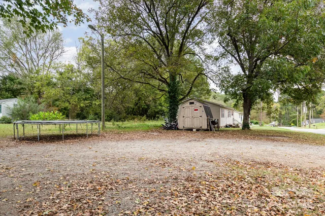 a view of a house with a yard and large trees