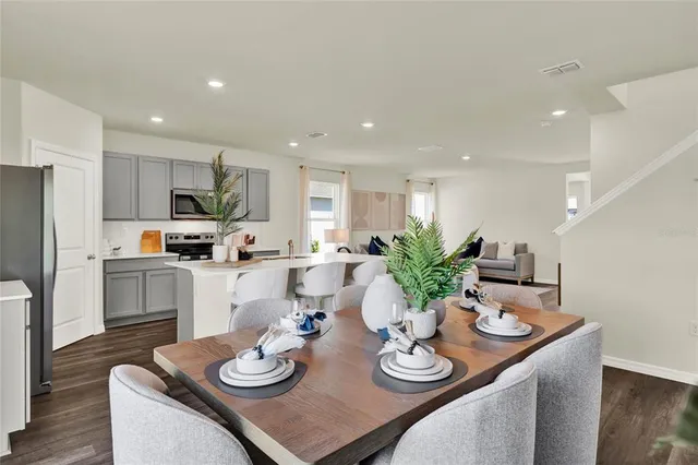a kitchen with stainless steel appliances granite countertop kitchen island stainless steel appliances sink refrigerator dining table and chairs