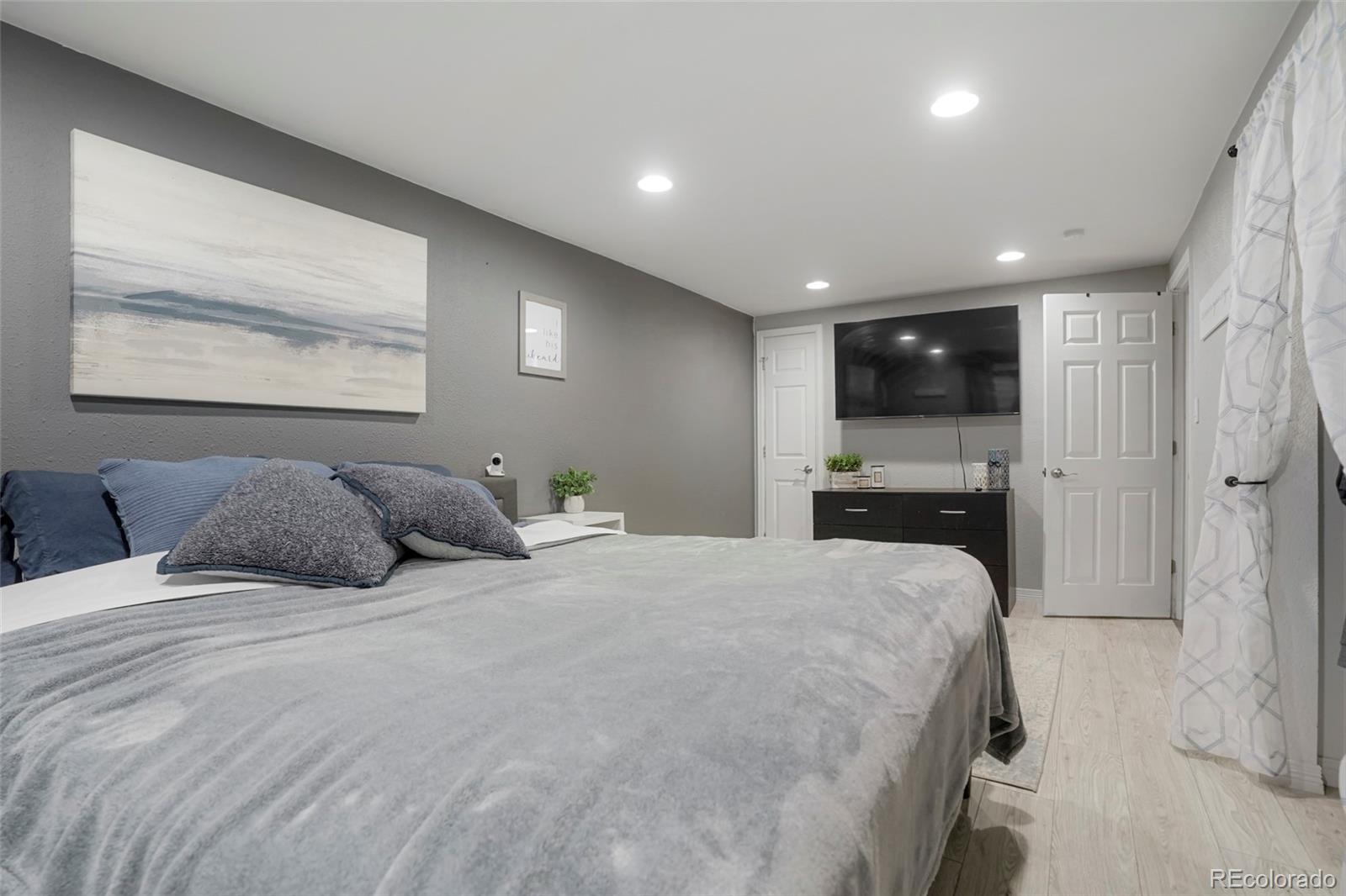 9201 West 104th Place Westminster, CO 80021 - Photo 12 of 29 a large bedroom with a large bed and a view of kitchen