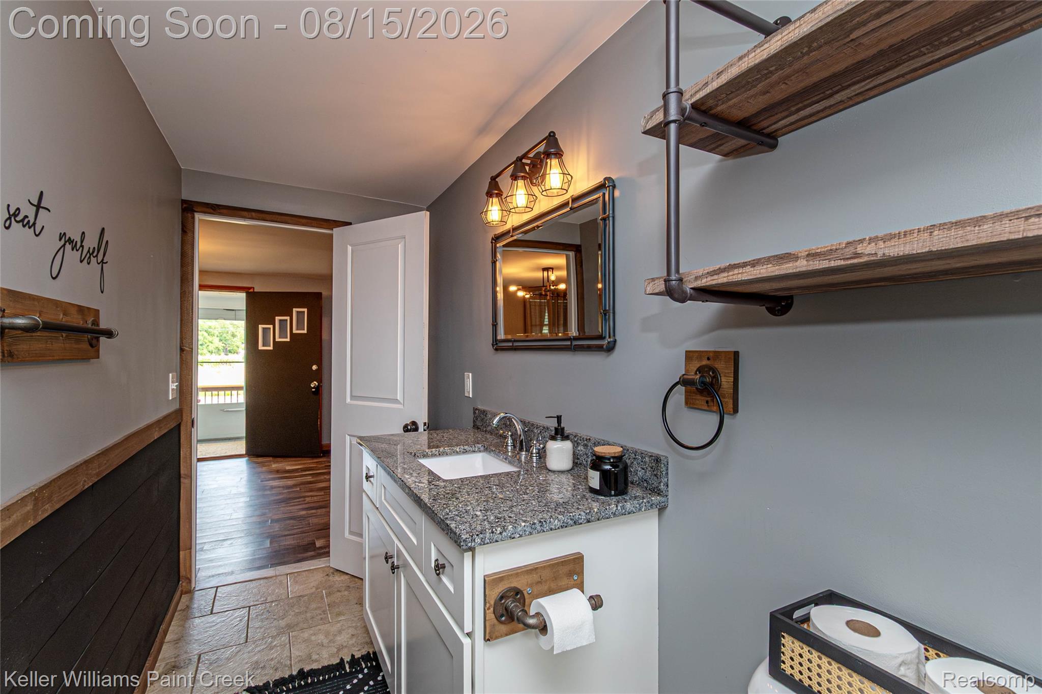 330 East Washington Street Romeo, MI 48065 - Photo 32 of 68 Vanity with a granite-style countertop and integrated sink, industrial-style wall sconce, and wood-finish shelving