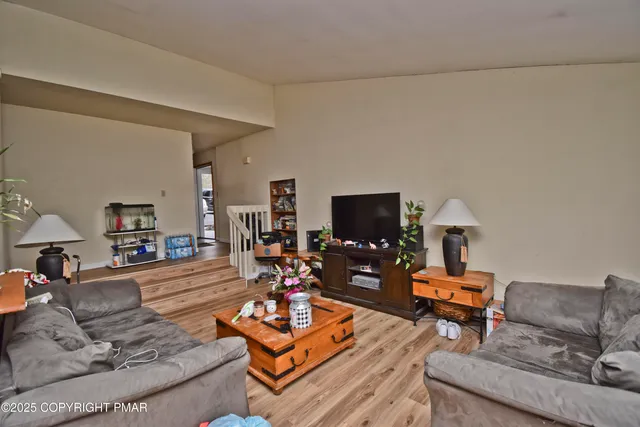 a living room with furniture a flat screen tv and a table