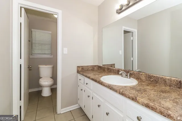 a bathroom with a granite countertop sink toilet and mirror